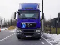 Niebieska ciężarówka z literą "L" na grillu, gotowa do drogi. Kierowca ciężarówek wyrusza w trasę.