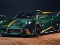Pagani Huayra w kolorze głębokiej zieleni z pomarańczowymi akcentami, prezentuje swoje karbonowe nadwozie na drewnianej podłodze.