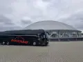 Czarny autokar turystyczny "Eurotrans" przed nowoczesnym budynkiem z kopułą.