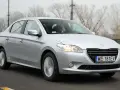 Srebrny Peugeot 301 jedzie po drodze, za kierownicą siedzi mężczyzna w okularach.