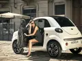 Elegancka kobieta w okularach przeciwsłonecznych wysiada z białego samochodu Microcar, idealnego na miejskie wypady bez prawa jazdy.