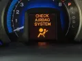 Na desce rozdzielczej świeci się pomarańczowa kontrolka poduszki powietrznej z napisem "CHECK AIRBAG SYSTEM" i ikoną pasażera.