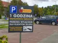 Tablica informuje o 1 godzinie darmowego parkingu dla klientów Biedronki. Pojazdy parkowane dłużej mogą otrzymać mandat za parkowanie i zostać odholowane.