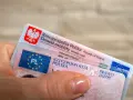 Dłoń trzyma polski dowód osobisty i prawo jazdy.
