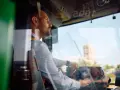 Skupiony kierowca autobusu prowadzi pojazd, trzymając kierownicę. Widać jego profil i fragment deski rozdzielczej.