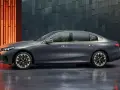 Eleganckie, szare BMW i5 z niebieskim akcentem na błotniku, prezentujące się na tle nowoczesnej, geometrycznej ściany.