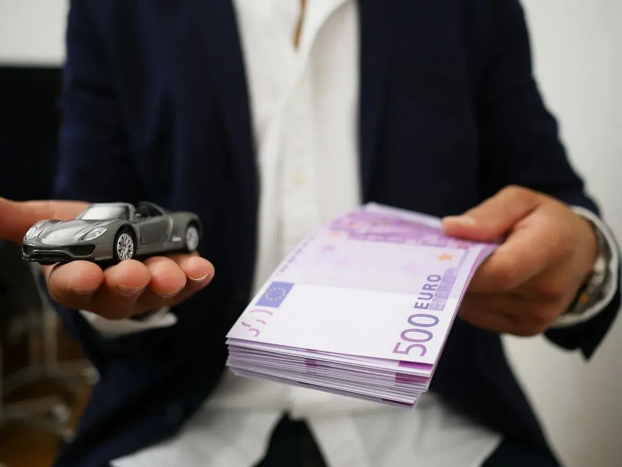 Model samochodu i stos banknotów 500 euro. Symbolizuje to cesję leasingu, gdzie nowy właściciel przejmuje zobowiązania.