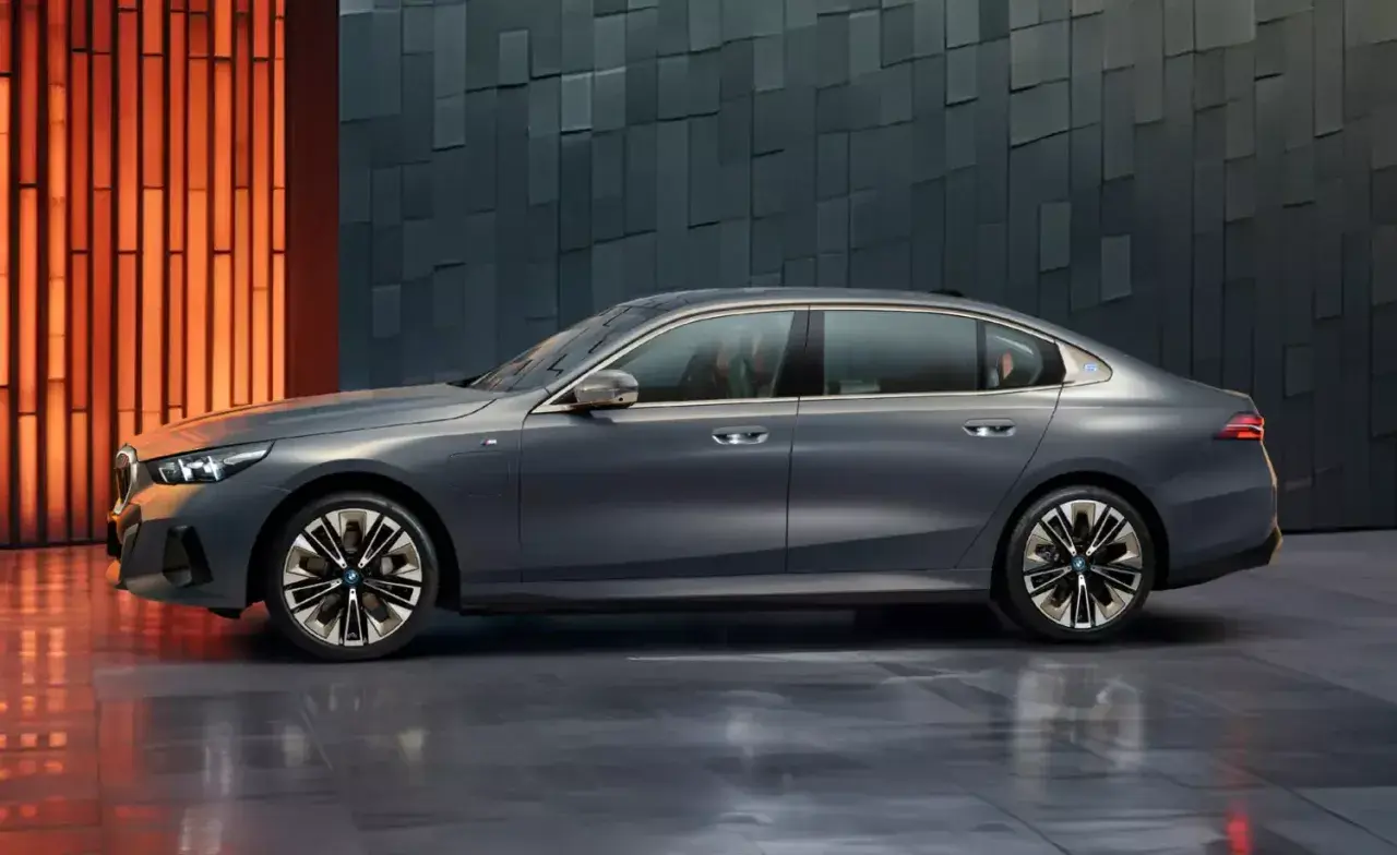 Eleganckie, szare BMW i5 z niebieskim akcentem na błotniku, prezentujące się na tle nowoczesnej, geometrycznej ściany.