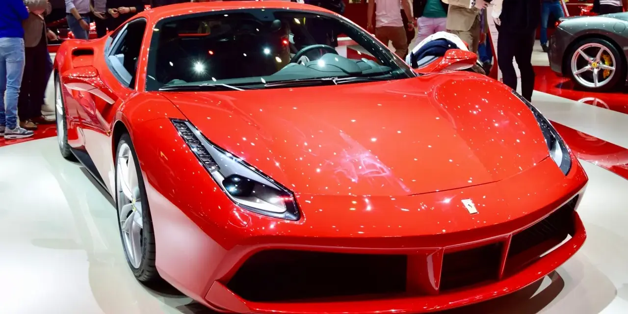 Błyszczące, czerwone Ferrari 488 na wystawie, otoczone przez widzów.