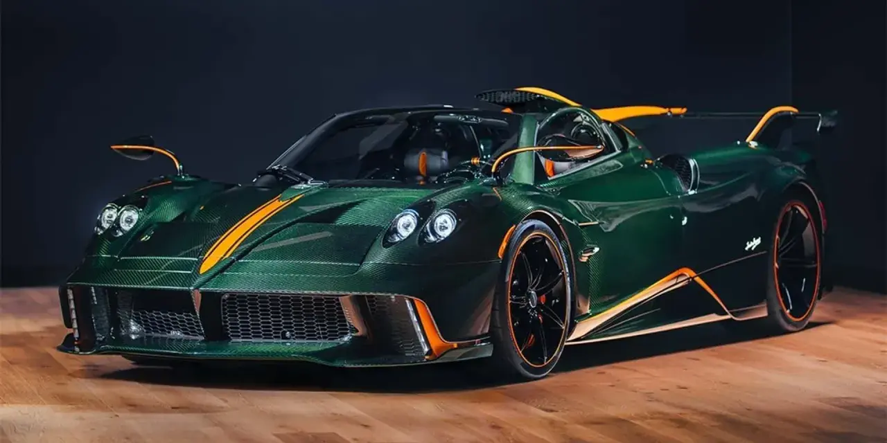 Pagani Huayra w kolorze głębokiej zieleni z pomarańczowymi akcentami, prezentuje swoje karbonowe nadwozie na drewnianej podłodze.