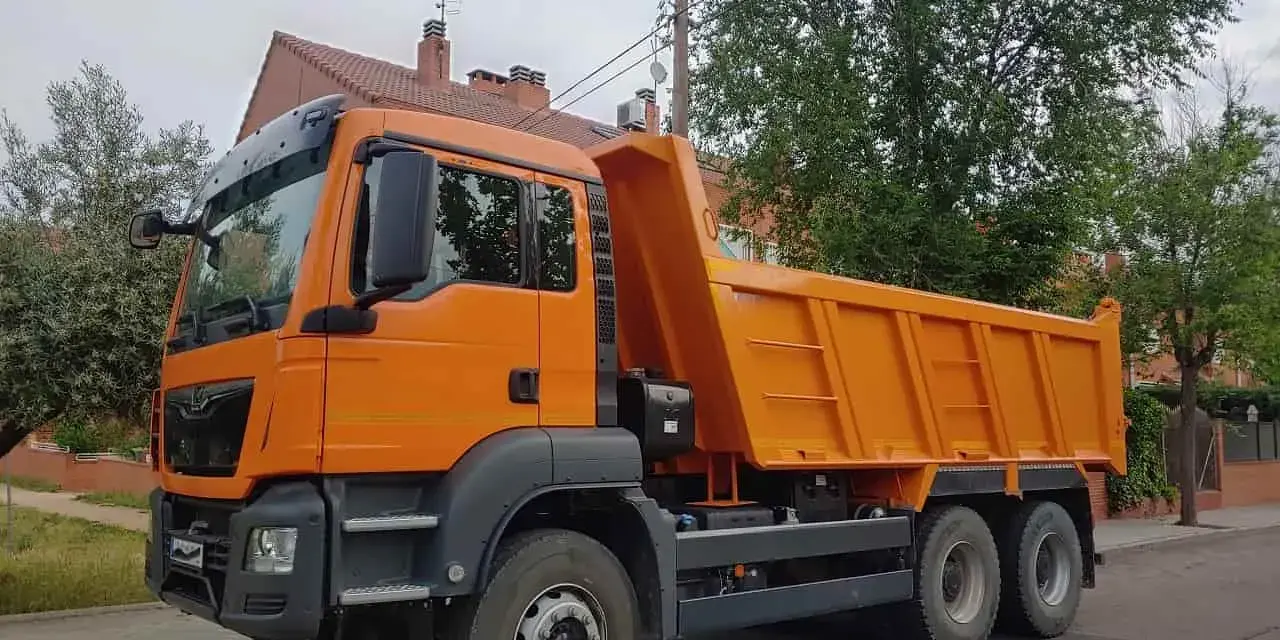 Pomarańczowy wywrotka c1 stoi na ulicy, gotowa do pracy.
