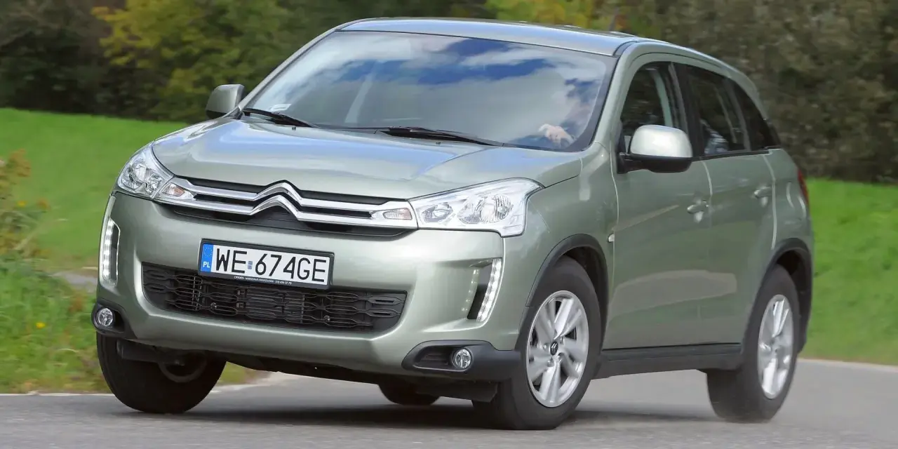 Zielony Citroën C4 Aircross z polskimi tablicami WE 674GE jedzie po drodze wśród zieleni.