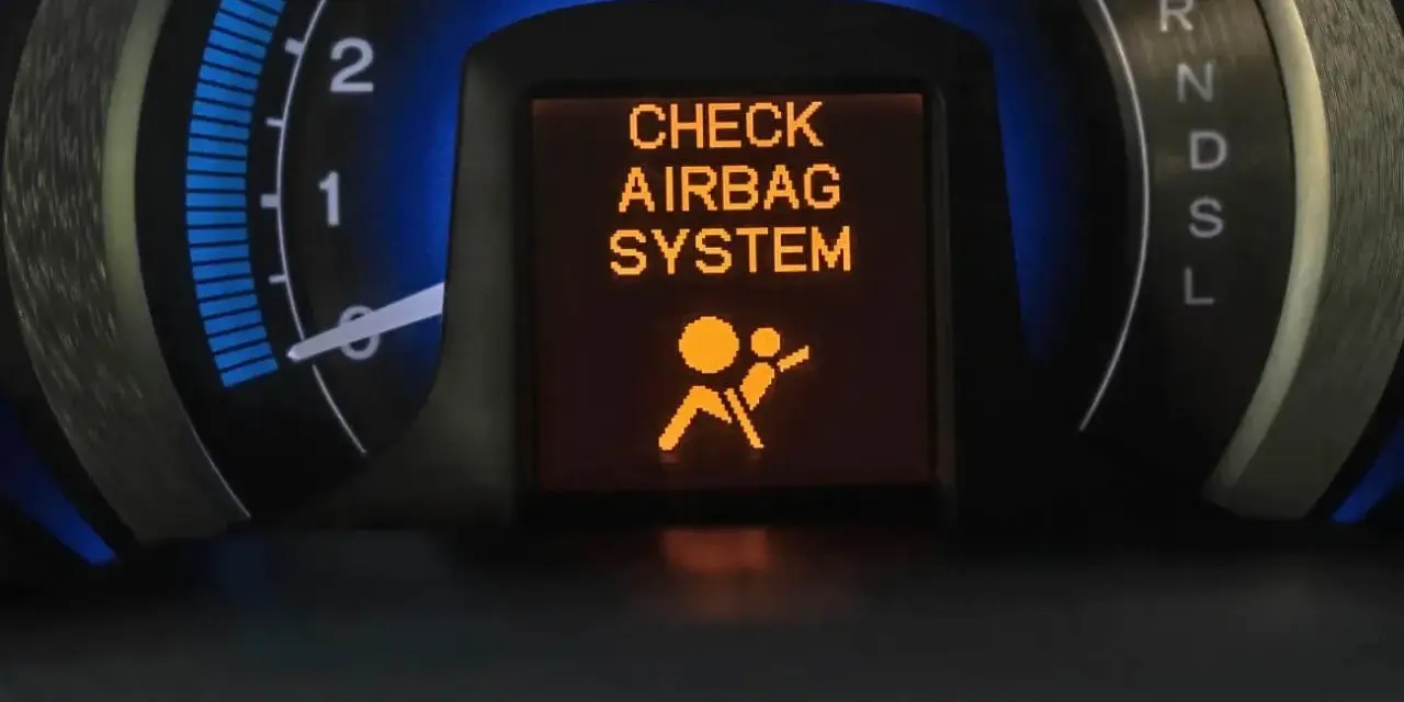 Na desce rozdzielczej świeci się pomarańczowa kontrolka poduszki powietrznej z napisem "CHECK AIRBAG SYSTEM" i ikoną pasażera.