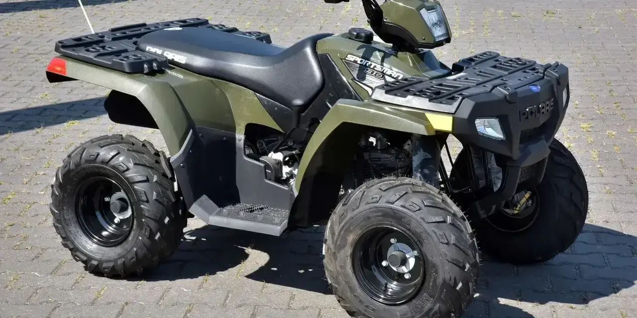 Zielony quad Polaris Sportsman 300 na kostce brukowej.