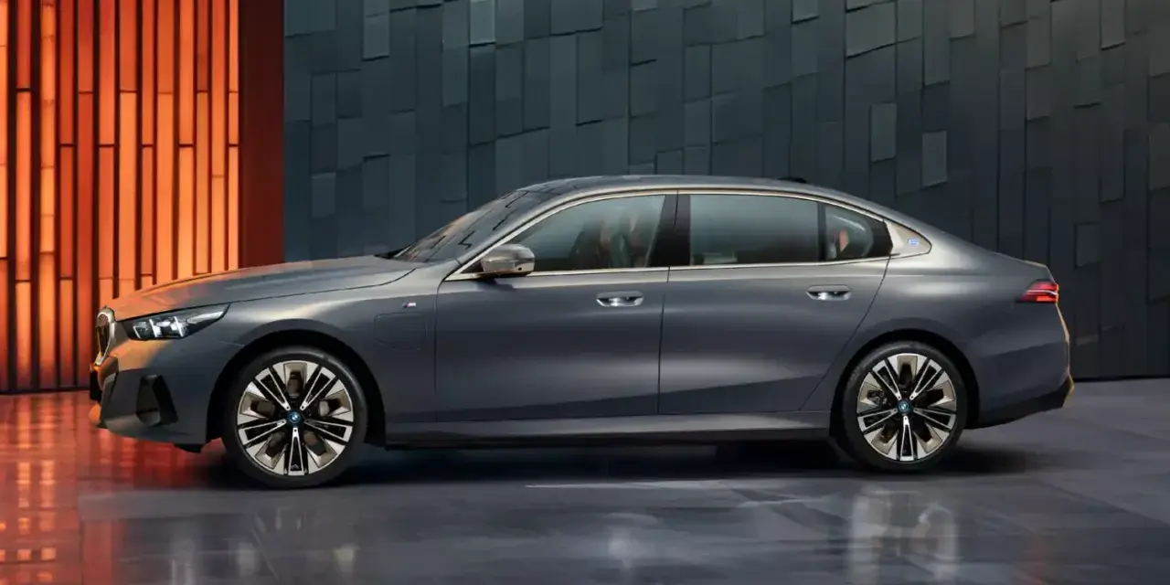 Eleganckie, szare BMW i5 z niebieskim akcentem na błotniku, prezentujące się na tle nowoczesnej, geometrycznej ściany.