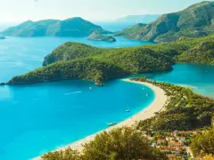 Turcja zachwyca turkusowym morzem i zielonymi wzgórzami. Widok na zatokę z plażą i górami.