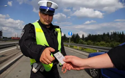 Policjant w kamizelce odblaskowej prosi o okazanie dokumentów. Czy trzeba mieć przy sobie prawo jazdy? Tak, podczas kontroli drogowej.