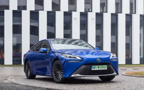 Niebieski samochód Toyota Mirai na tle nowoczesnego budynku.