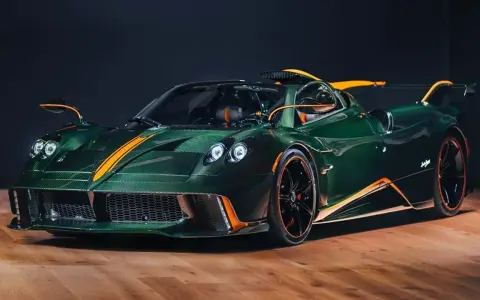 Pagani Huayra w kolorze głębokiej zieleni z pomarańczowymi akcentami, prezentuje swoje karbonowe nadwozie na drewnianej podłodze.