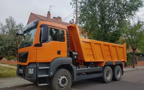 Pomarańczowy wywrotka c1 stoi na ulicy, gotowa do pracy.