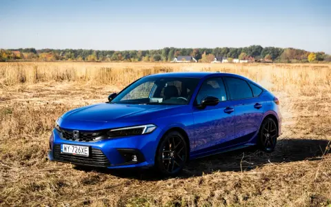 Błękitny Honda Civic 11. generacji na tle jesiennego pola.