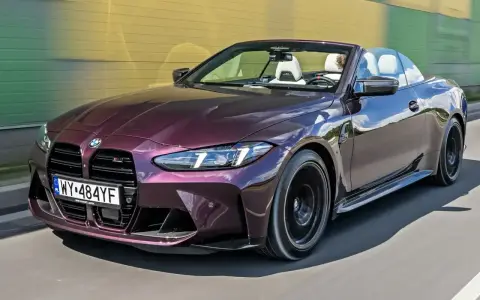 Fioletowe sportowe auta BMW M4 kabriolet pędzi po drodze.