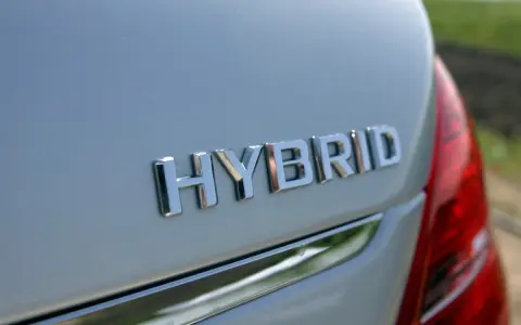 Chromowane napisy "HYBRID" na białym nadwoziu samochodu. To nowoczesny hybrydowy pojazd elektryczny, gotowy na ekologiczną podróż.