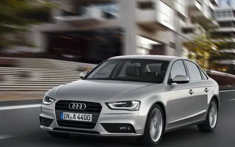 Srebrne Audi A4 B8 w ruchu miejskim, z rozmytym tłem budynków.