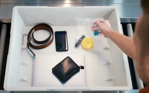 Przedmioty do kontroli bezpieczeństwa na lotnisku: pasek, telefon, portfel, laptop i kosmetyki w woreczku.