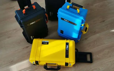 Trzy walizki Peli Air: czarna, niebieska i żółta, na drewnianej podłodze.