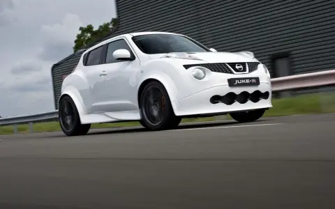 Biały Nissan Juke-R pędzi po torze, jego sportowy wygląd podkreślają szerokie nadkola i agresywny przedni zderzak.