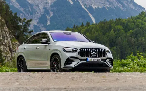 Biały Mercedes GLE 53 AMG coupe na tle górskiego krajobrazu z lasem.