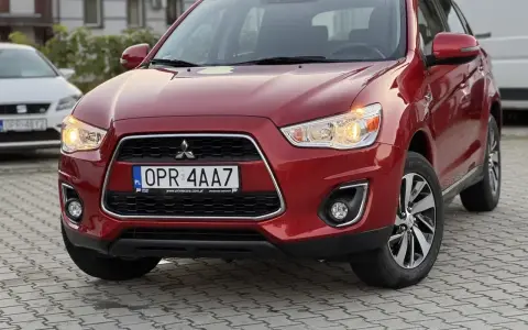 Czerwone Mitsubishi ASX z przodu, z tablicą rejestracyjną OPR 4AA7.