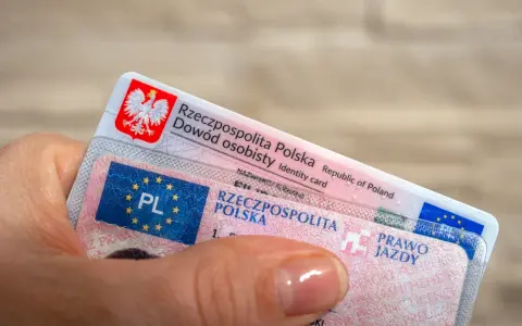 Dłoń trzyma polski dowód osobisty i prawo jazdy.