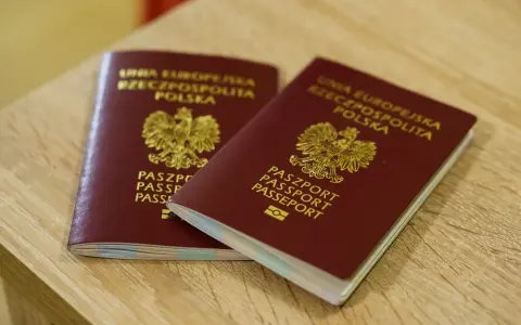 Dwa polskie paszporty leżące na drewnianym blacie.
