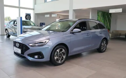 Niebieski Hyundai i30 Wagon z 2015 roku stoi w salonie samochodowym.