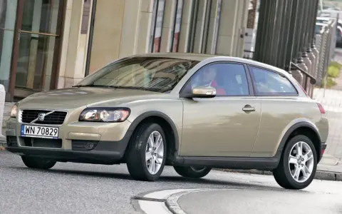 Złoty Volvo C30 z polskimi tablicami rejestracyjnymi WN 70829 jedzie po miejskiej ulicy.