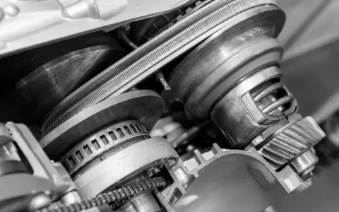 Zbliżenie na mechanizm bezstopniowej skrzyni biegów z widocznym pasem i kołami pasowymi.