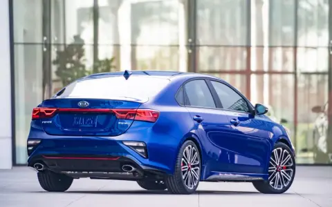 Niebieski sedan Kia Forte z widokiem z tyłu, z czerwonymi akcentami i sportowymi felgami.