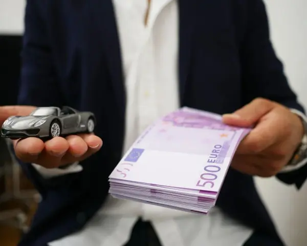 Model samochodu i stos banknotów 500 euro. Symbolizuje to cesję leasingu, gdzie nowy właściciel przejmuje zobowiązania.