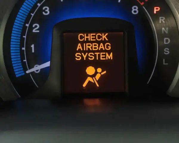 Na desce rozdzielczej świeci się pomarańczowa kontrolka poduszki powietrznej z napisem "CHECK AIRBAG SYSTEM" i ikoną pasażera.