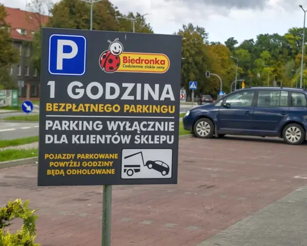 Tablica informuje o 1 godzinie darmowego parkingu dla klientów Biedronki. Pojazdy parkowane dłużej mogą otrzymać mandat za parkowanie i zostać odholowane.