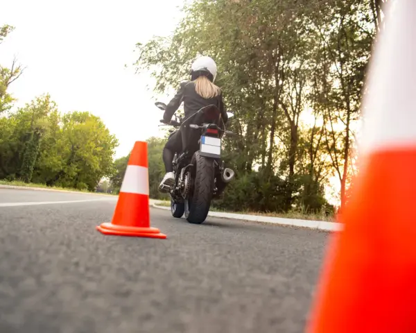 Kobieta na motocyklu podczas egzaminu na prawo jazdy kat A. Sprawdza cenę kursu.