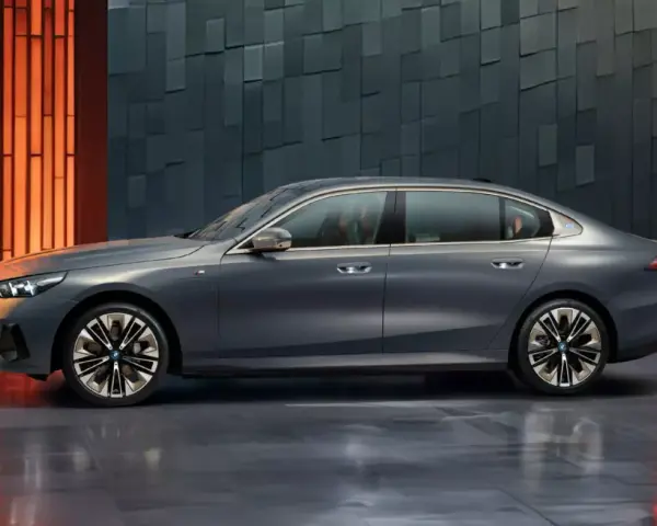Eleganckie, szare BMW i5 z niebieskim akcentem na błotniku, prezentujące się na tle nowoczesnej, geometrycznej ściany.