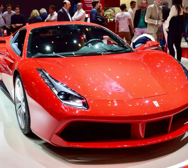 Błyszczące, czerwone Ferrari 488 na wystawie, otoczone przez widzów.
