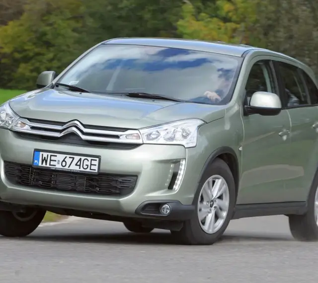 Zielony Citroën C4 Aircross z polskimi tablicami WE 674GE jedzie po drodze wśród zieleni.
