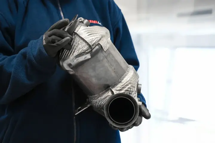 Osoba w rękawiczkach trzyma filtr cząstek stałych DPF.