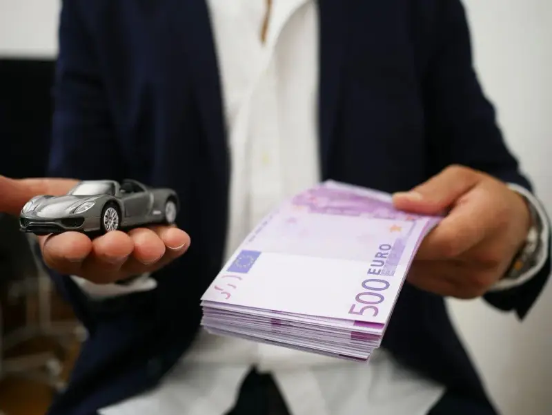 Model samochodu i stos banknotów 500 euro. Symbolizuje to cesję leasingu, gdzie nowy właściciel przejmuje zobowiązania.